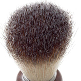 A barber shaving brush with a wooden handle and badger hair bristles.