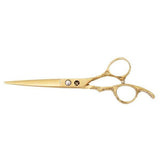 A pair of gold-colored hairdressing scissors with a dragon handle design and a large blue gemstone on the ring.