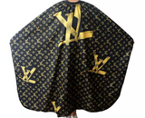 Black and gold patterned barber's cape with elastic, hook, and snap buttons on the neck closure