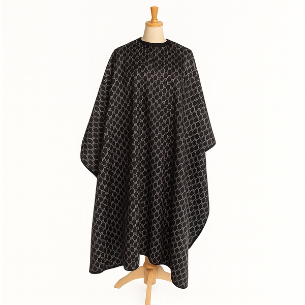 Black patterned hairdressing cape on a wooden mannequin against a white background