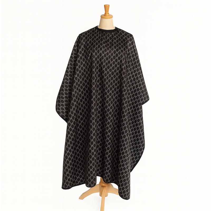 Black patterned hairdressing cape on a wooden mannequin against a white background