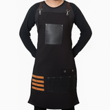 Black apron with brown accents worn by a person on a white background